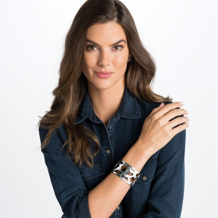 Model wearing a Brighton silver-plated cuff bracelet with animal print inlay and openwork silver-plated design