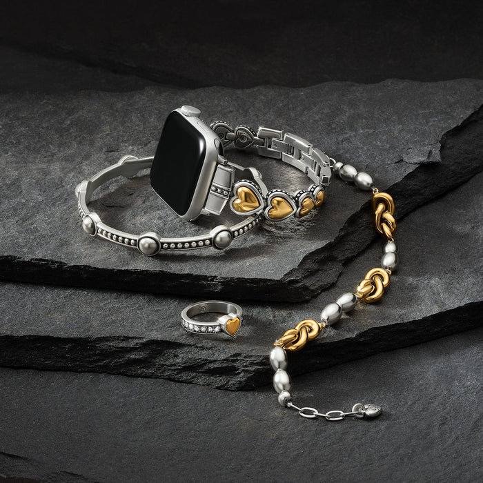 Brighton smartwatch band styled with a two-tone heart bracelet and crystal ring on dark slate stones