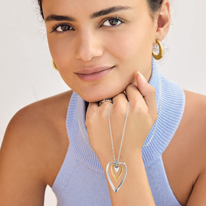 Model wearing a Brighton two-tone heart pendant necklace with crystal accents and coordinating Brighton accessories