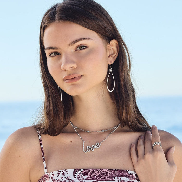 Model wearing Brighton silver-plated teardrop earrings with crystal love script necklace and coordinating Brighton accessories