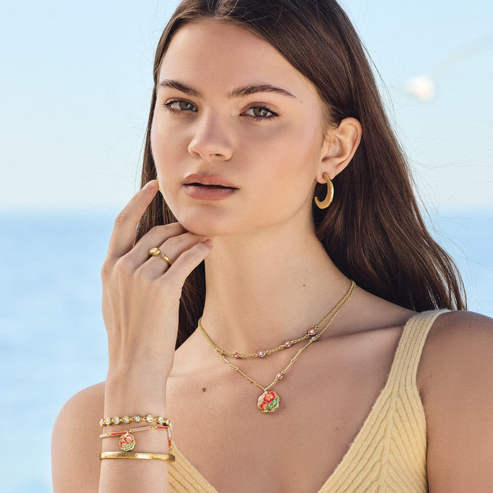 Model wearing Brighton gold-plated hoop earrings with floral enamel pendant necklace and coordinating Brighton accessories