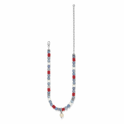 Brighton beaded necklace with blue, white, and red beads, pearl drop, and silver-plated chain on a white background