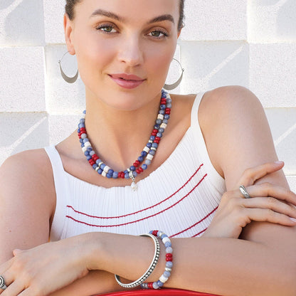 Model wearing a Brighton beaded necklace with blue, red, and white stones and coordinating Brighton accessories