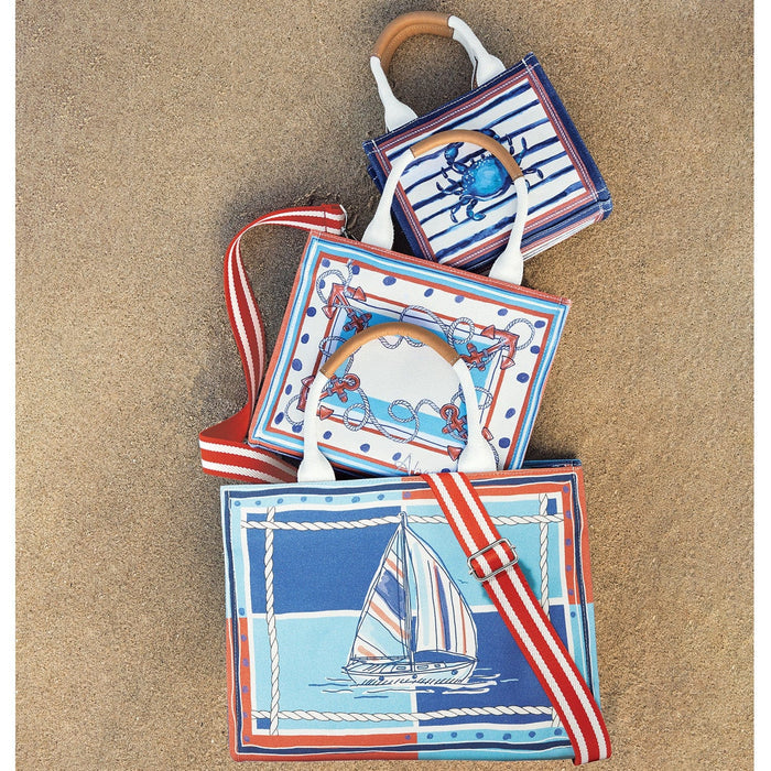 Brighton nautical tote bags styled with sailboat, anchor, and crab prints in red, white, and blue on sand