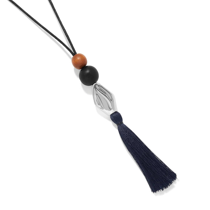 Brighton pendant necklace with wood beads, silver-plated accent, and navy tassel on black nylon cord on a white background