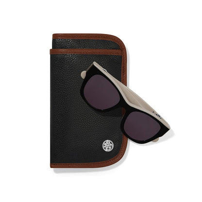 Brighton black leather eyeglass case with brown trim styled with black sunglasses on a white background