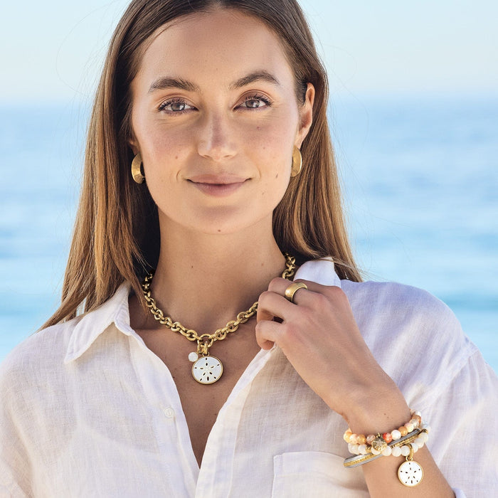 Model wearing a Brighton gold-plated chain necklace with mother-of-pearl sand dollar pendant and coordinating Brighton accessories