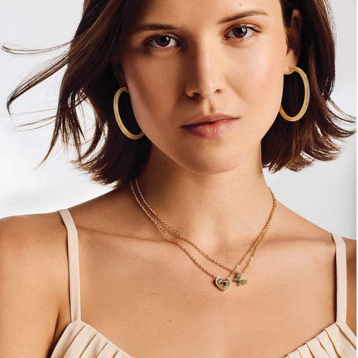 Model wearing Brighton gold-plated crystal hoop earrings with coordinating layered heart and butterfly pendant necklaces