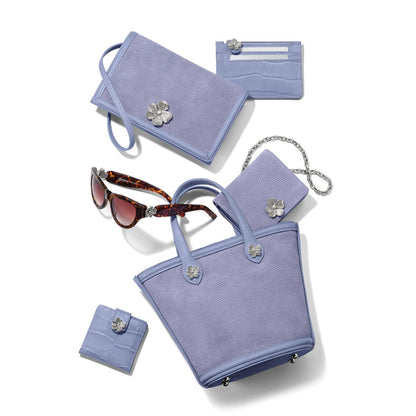 Brighton lavender handbag styled with matching wallets and tortoise sunglasses featuring silver flower accents on white