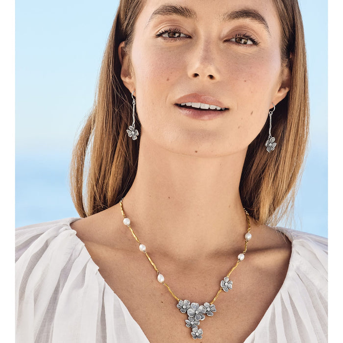 Model wearing a Brighton gold-plated necklace with pearls and silver flowers paired with matching silver flower drop earrings