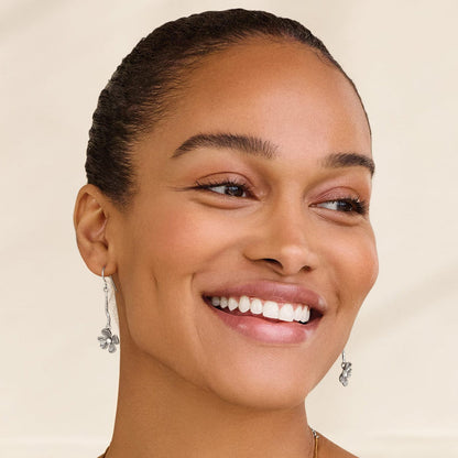 Model wearing Brighton silver-plated drop earrings with floral charm and crystal accent