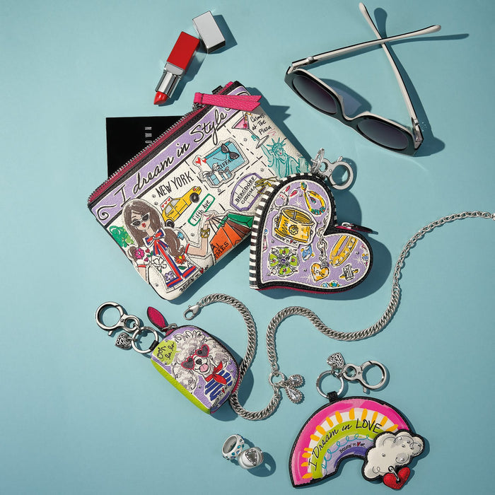 Brighton leather pouch with illustrated New York print, styled with sunglasses and other accessories on blue background
