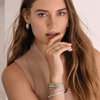 Model wearing Brighton two-tone hoop earrings with coordinating Brighton ring and stacked silver and gold bangles