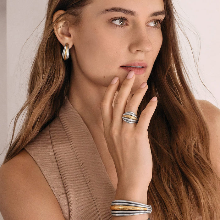 Model wearing Brighton two-tone hoop earrings with coordinating two-tone ring and stacked bangle bracelets in silver and gold