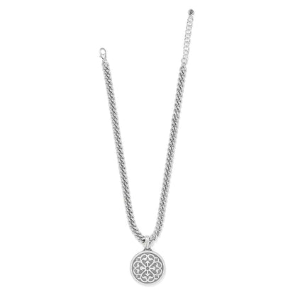 Brighton pendant necklace with silver-plated curb chain and round openwork medallion with scroll design on a white background