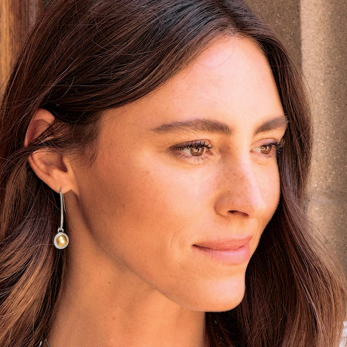 Model wearing a Brighton drop earring with two-tone finish featuring a silver frame and gold center bead