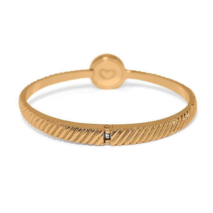 Brighton bangle bracelet with gold-plated ribbed band, round heart-engraved station, and crystal accent on a white background