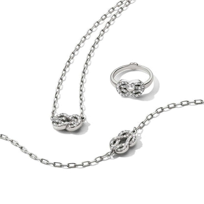 Brighton silver-plated jewelry set styled with matching knot necklace, bracelet, and ring featuring crystals on white background