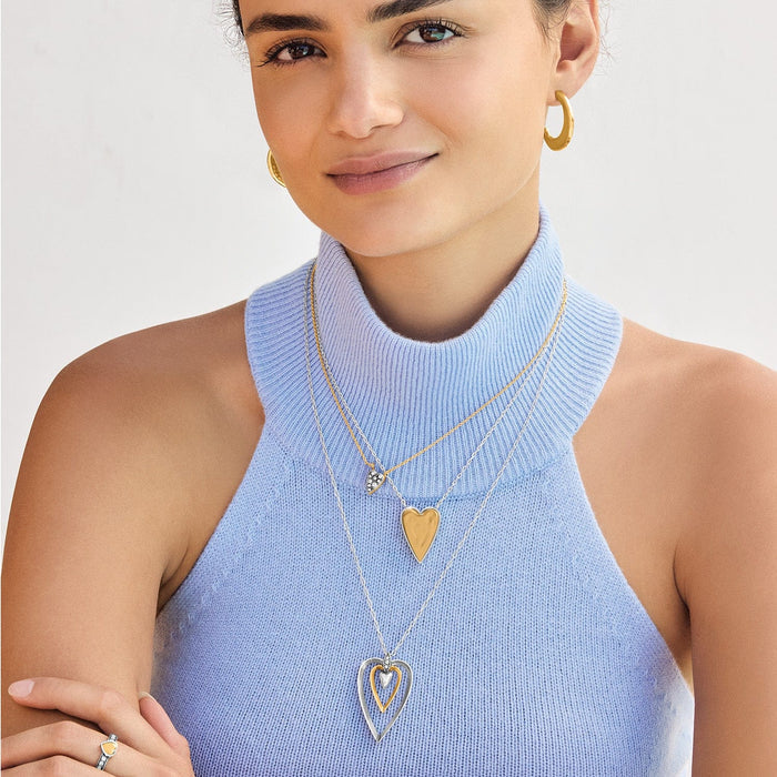 Model wearing layered Brighton two-tone heart pendant necklaces with crystal accents and coordinating Brighton accessories