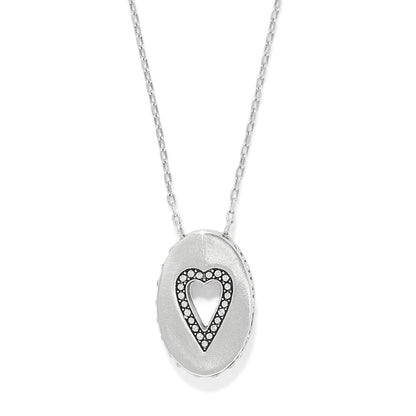 Brighton pendant necklace with silver-plated oval medallion featuring cut-out heart outlined in crystals on a white background