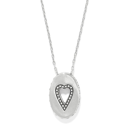 Brighton pendant necklace with silver-plated oval medallion featuring cut-out heart outlined in crystals on a white background