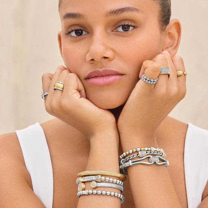 Model wearing Brighton silver and gold-plated rings with crystal accents and coordinating Brighton bracelets stacked on wrists