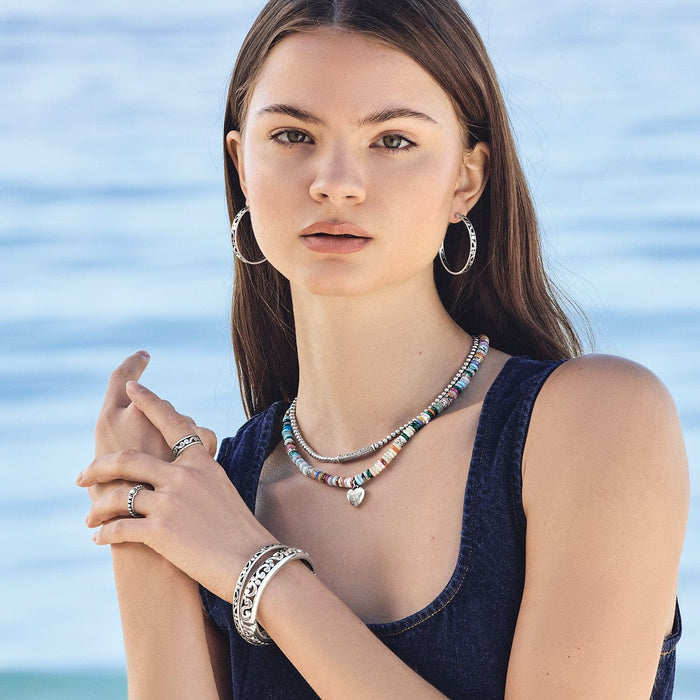 Model wearing a Brighton multicolor beaded necklace with silver-plated heart charm and coordinating Brighton accessories