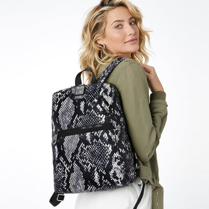 Model with a Brighton backpack in black and white snakeskin print with front zip pocket