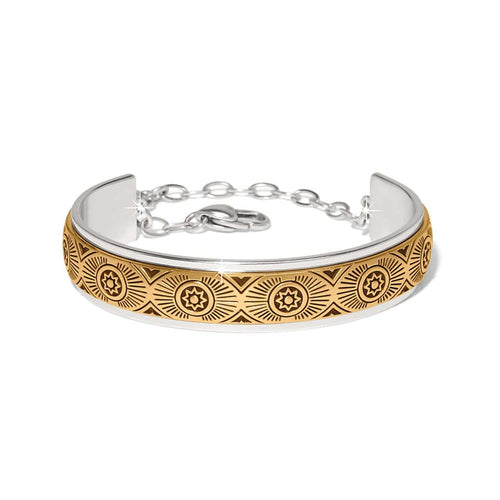 Brighton cuff bracelet with two-tone finish featuring engraved gold sunburst medallion pattern and silver chain closure on a white background