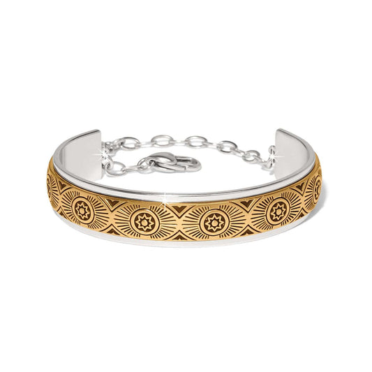 Brighton cuff bracelet with two-tone finish featuring engraved gold sunburst medallion pattern and silver chain closure on a white background