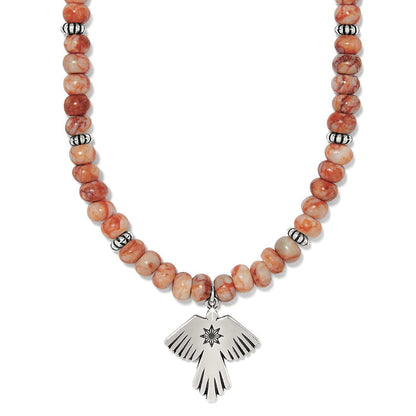 Brighton beaded necklace with orange marbled stone beads, silver-plated spacers, and thunderbird pendant on a white background