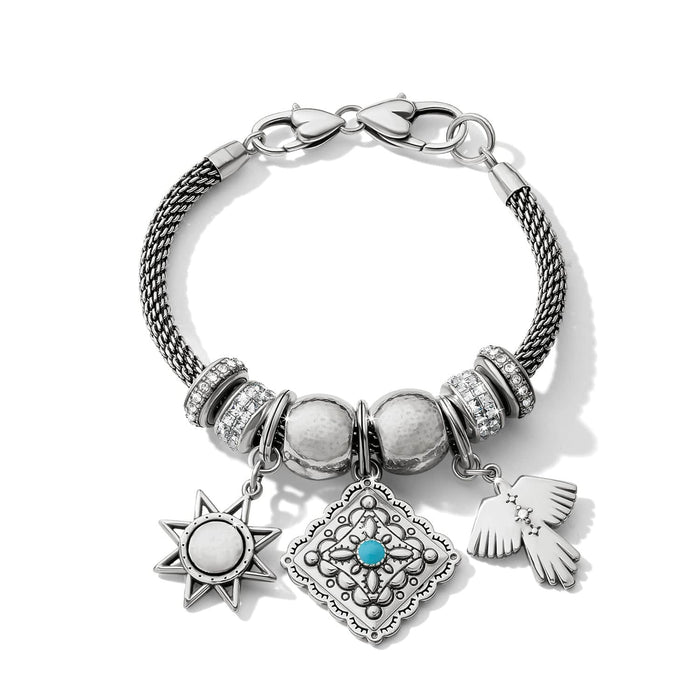Brighton charm bracelet with silver-plated mesh band, crystal accents, star, medallion, and bird charms on a white background
