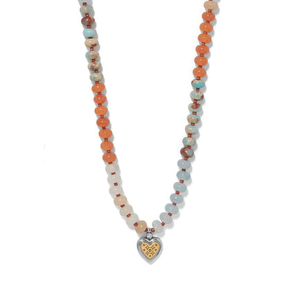 Brighton beaded necklace with orange, blue, and cream stones and two-tone heart pendant with crystal on a white background