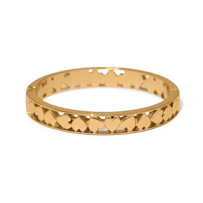 Brighton bangle bracelet with gold-plated finish and cut-out heart pattern around the band on a white background