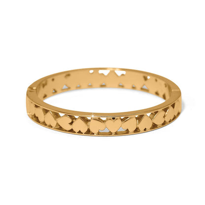 Brighton bangle bracelet with gold-plated finish and cut-out heart pattern around the band on a white background