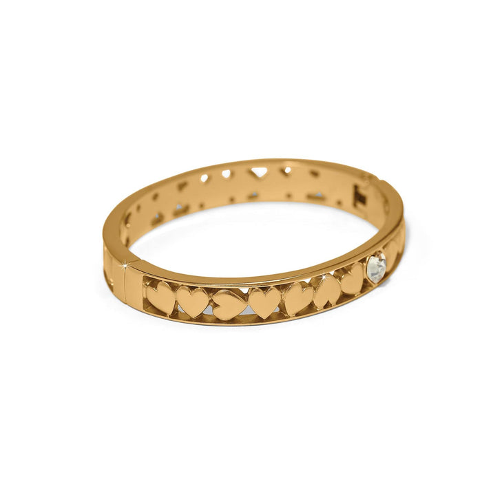 Brighton gold-plated bangle bracelet with raised heart motifs and a single crystal accent on a white background