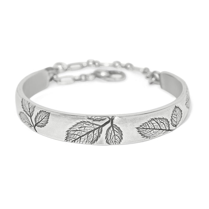 Brighton bangle bracelet with silver-plated finish, embossed leaf designs, and adjustable chain closure on a white background