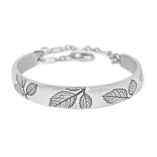 Brighton bangle bracelet with silver-plated finish, embossed leaf designs, and adjustable chain closure on a white background