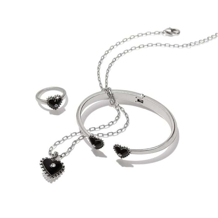 Brighton jewelry set with silver-plated bangle, ring, and heart pendant necklace featuring black hearts and crystals on a white background