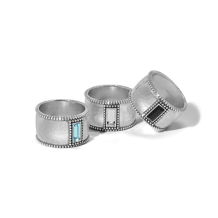 Brighton silver-plated wide band rings with blue, clear, and black crystal baguettes and beaded edges on a white background