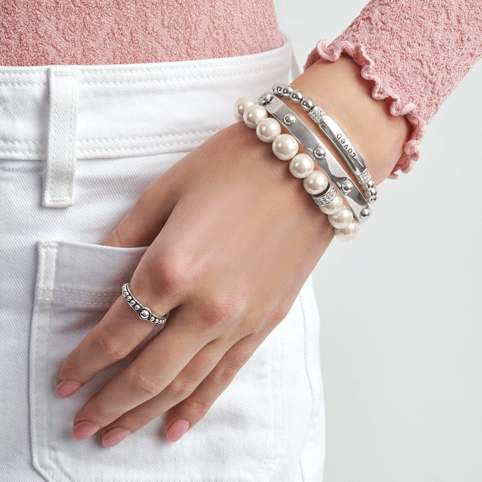 Model wearing Brighton silver-plated bracelets with pearl beads and engraved bar, paired with a silver-plated beaded ring
