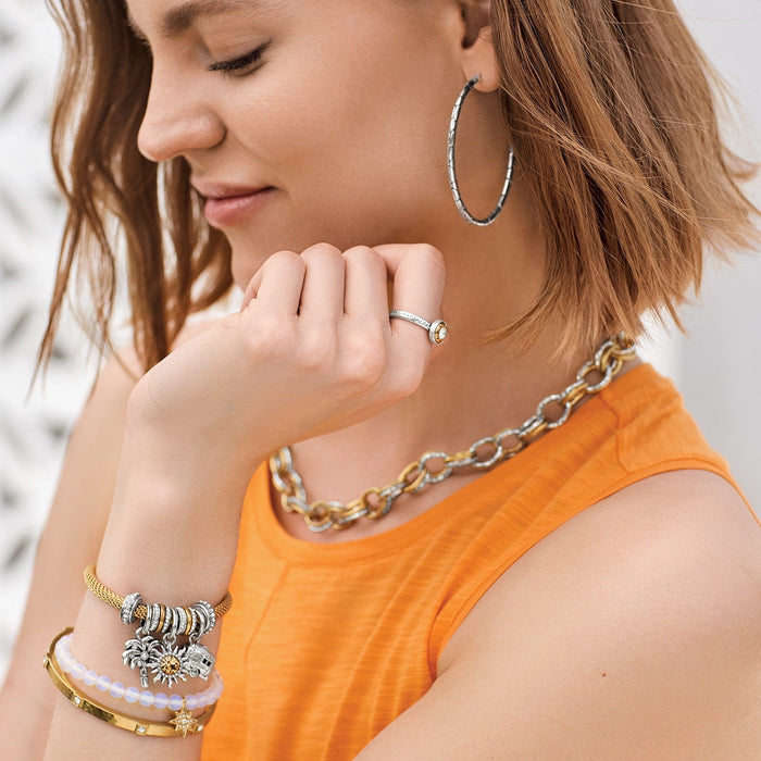 Model wearing a Brighton silver-plated charm bracelet with sun and palm tree charms and coordinating Brighton accessories