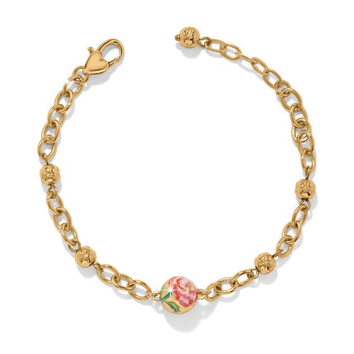Brighton gold-plated chain bracelet with floral enamel bead, beaded stations, and heart-shaped clasp on a white background