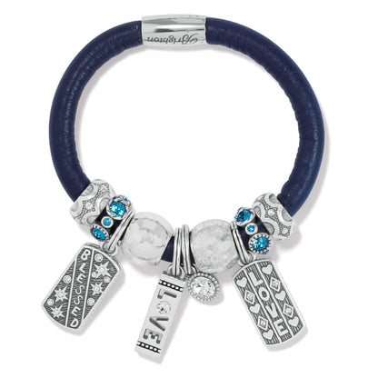 Brighton charm bracelet with navy leather band, silver-plated charms, blue crystal beads, and Love Blessed tags on a white background