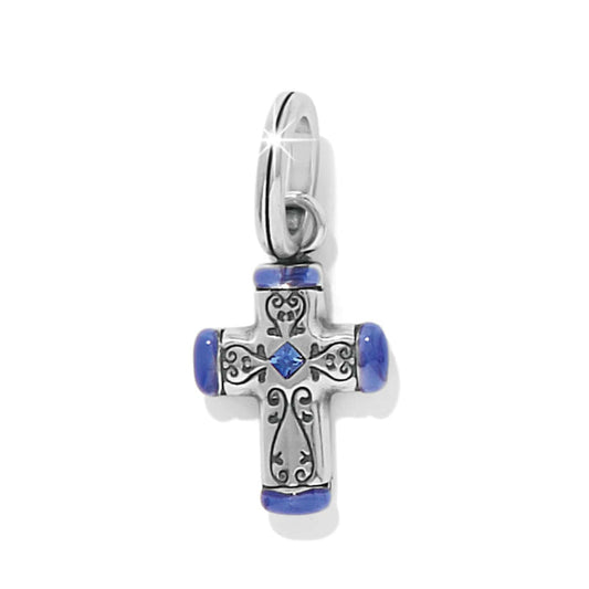 Brighton cross charm with silver-tone scrollwork, blue enamel tips, and blue crystal center on a white background
